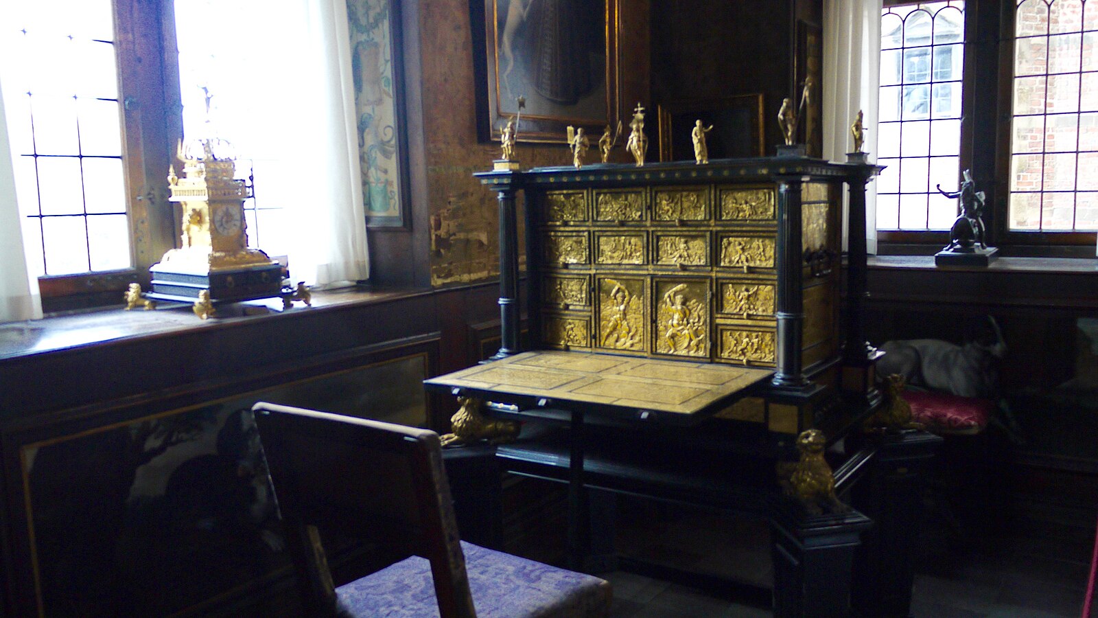 photograph of an arnate desk with many carvings and a chair infront of it